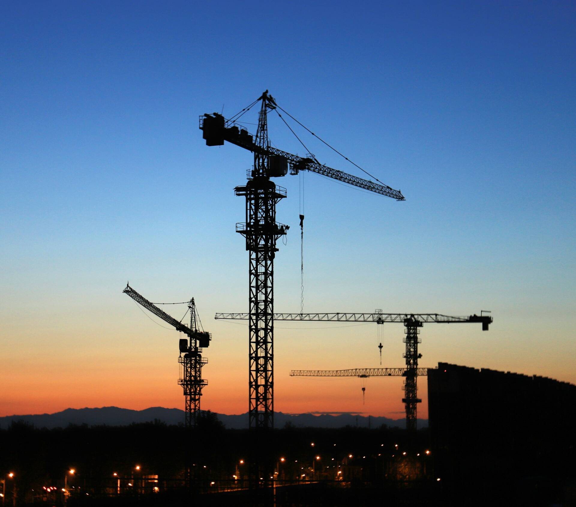 Tower cranes over a construction site at golden hour — Axis Construction